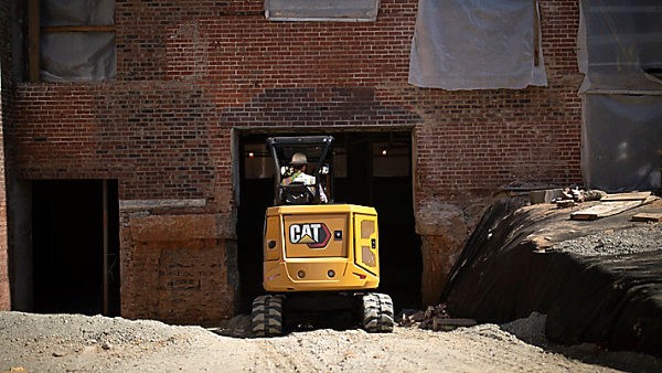 excavator entering garage door of brick building