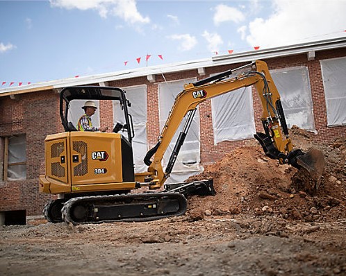 Mini excavator digging into dirt pile