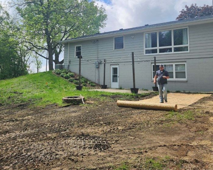 Trever Friel rolling out grass mat behind home