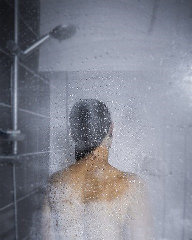 Woman in shower with steam on glass